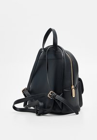 Zaino in pelle nera con finitura testurizzata, dotato di accessori in metallo color oro, spallacci regolabili e dettaglio con zip laterale.