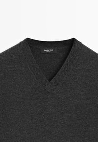 Pull gris foncé en col en V avec col côtelé, montrant l'étiquette de la marque Massimo Dutti cousue à l'intérieur de l'encolure.