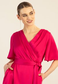 Fuchsia Wickelkleid aus glattem Stoff, mit kurzen Ärmeln, V-Ausschnitt, gebundenem Taillenbund und seitlichen Taschen.