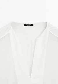 Biała bluzka z dekoltem w literę V, wykonana z lekkiego materiału. Posiada metkę przy dekolcie z logo "Massimo Dutti".