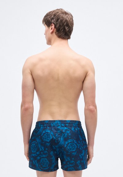 Μπλε μαγιό με σχέδιο λουλουδιών, ελαστική μέση, ομαλή υφή, μήκος μέχρι το μέσο του μηρού και χωρίς εμφανή εξαρτήματα.