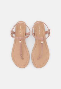 Sandales plates roses avec des lanières délicates et un design à l'avant. Présente un petit accent en perle et une semelle intérieure en cuir tan rembourrée.