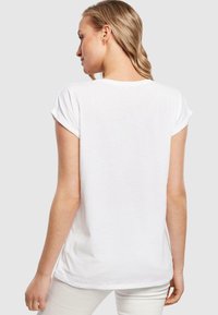 White cotton t-shirt with rolled short sleeves, rounded neckline, and a relaxed fit. Smooth texture and minimal design, no visible patterns.