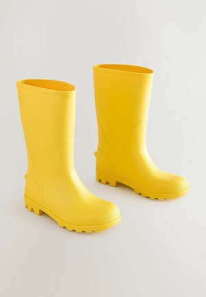 Bottes de pluie en caoutchouc jaunes avec une finition lisse, un tige haute, des semelles épaisses et un motif de semelle pour une adhérence sur les surfaces humides.