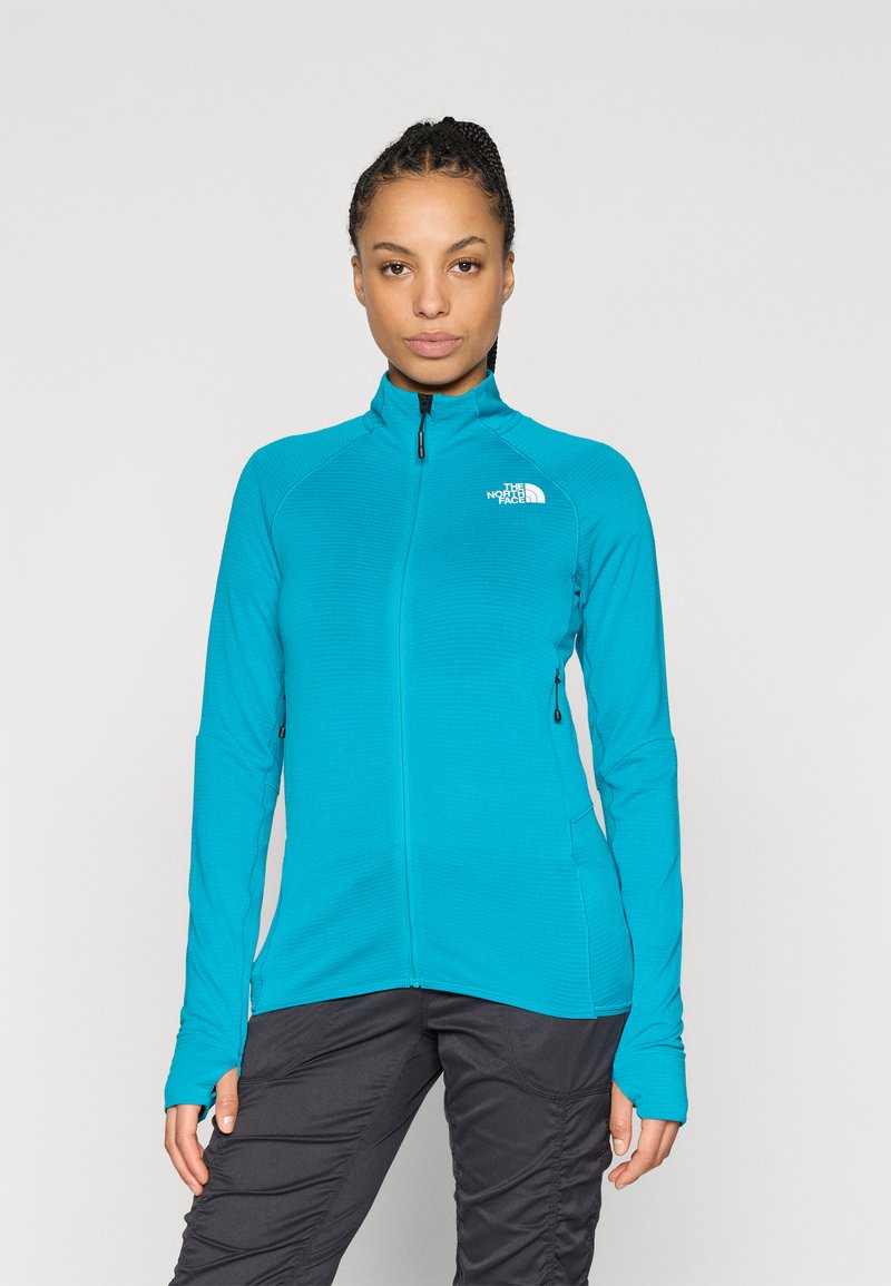 Τζάκετ σε χρώμα πετρόλ με φερμουάρ, υψηλό γιακά και μακριά μανίκια, με υφή σχεδίου και λογότυπο στο αριστερό στήθος.