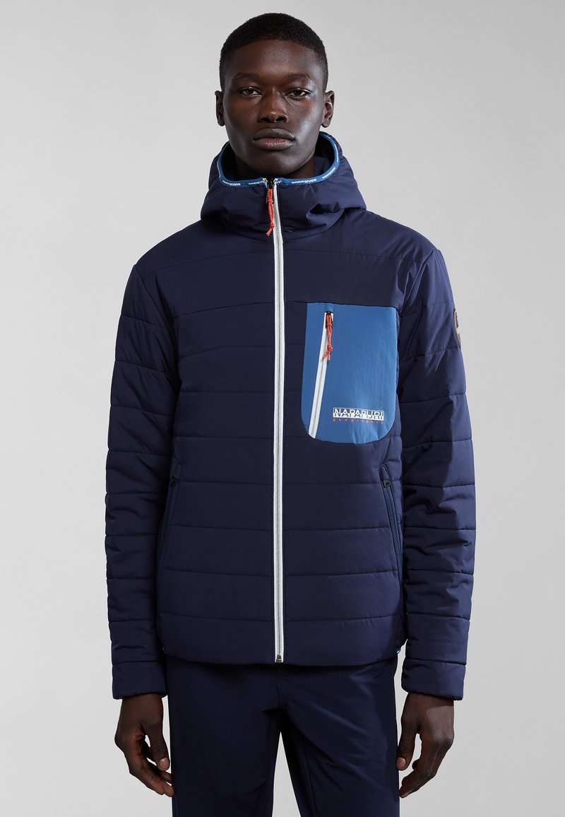 Giacca a vento navy con tasca sul petto blu, zip bianca e tirazip arancione. Presenta un cappuccio e una texture trapuntata su tutta la superficie.