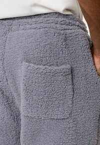 Grijze fleece broek met een gestructureerde afwerking, voorzien van een zijzak aan de rechterkant en een elastische tailleband.