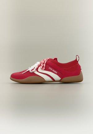 Baskets rouges Steve Madden avec des rayures blanches, des lacets roses et une semelle marron, vues de côté sur un fond uni.
