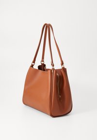 Sac à main en cuir marron avec deux sangles pour l'épaule, texture lisse, forme angulaire et une poche zippée sur un côté.