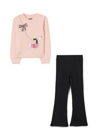Sweatshirt rose clair avec un graphisme de chien et un détail en nœud, associé à des leggings évasés noirs, tous deux en tissu doux et extensible.