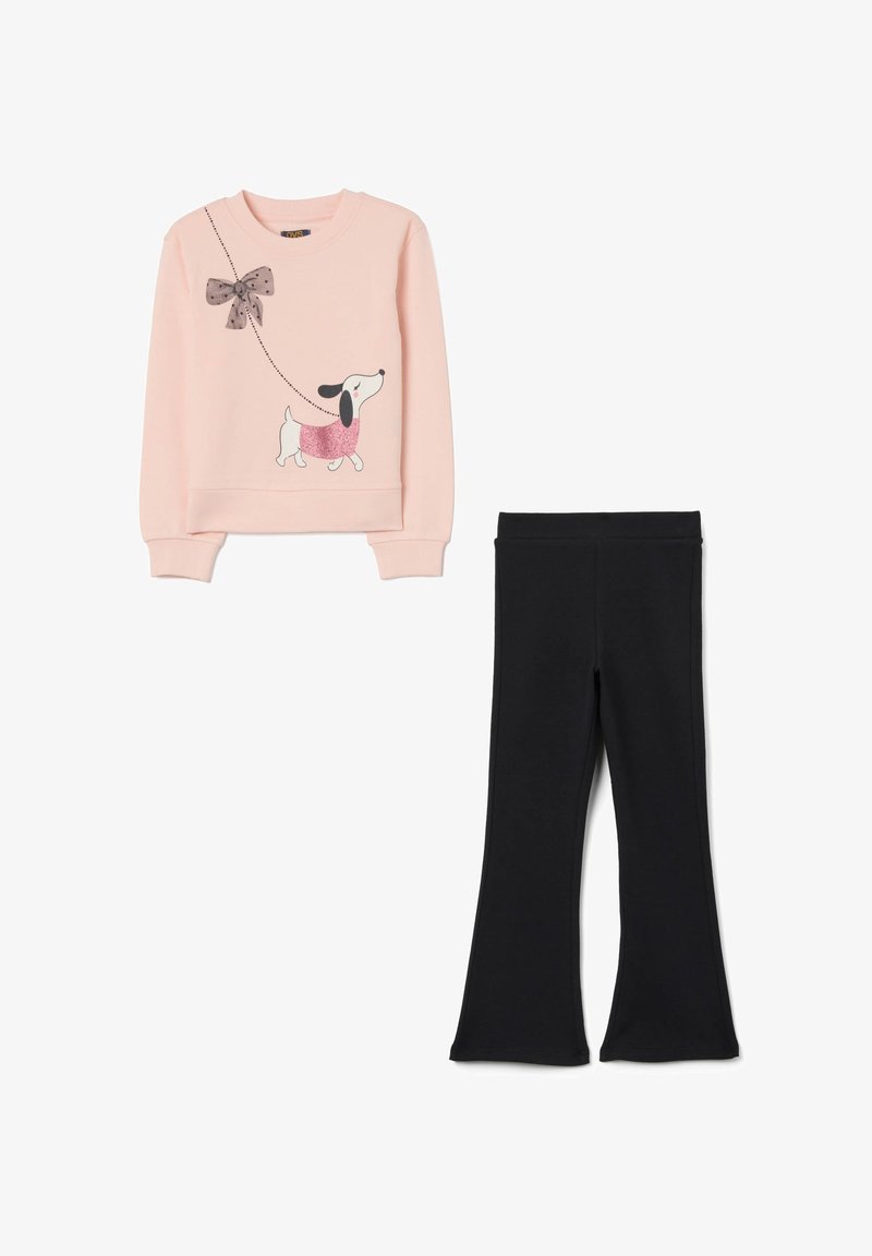 Sweatshirt rose clair avec un graphisme de chien et un détail en nœud, associé à des leggings évasés noirs, tous deux en tissu doux et extensible.