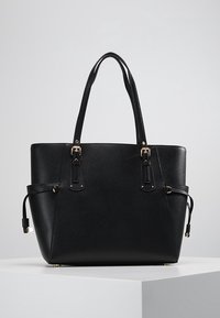 Sac fourre-tout en simili cuir noir avec deux poignées supérieures, accents en métal doré, forme structurée et liens latéraux ajustables. Texture lisse, sans motifs.