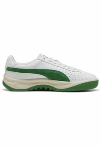 Baskets en cuir blanc avec des accents en suède vert, tige perforée, semelle épaisse verte et fermeture à lacets traditionnelle. Vue de profil.