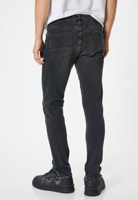 Svarta denimjeans med slim fit, bakfickor och en jämn textur. Komplett med svarta sneakers och en enkel vit skjorta.