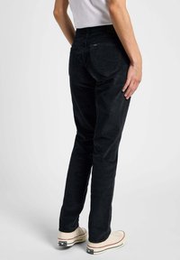 Czarne spodnie korduroy w slim fit, z tylnymi kieszeniami i subtelnymi detalami w szyciu, w zestawie z beżowymi butami z płótna.