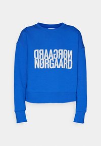 Sweat-shirt bleu à col rond avec manches longues et texte blanc « NØRGAARD » imprimé deux fois, une fois à l'envers au-dessus du texte normal.