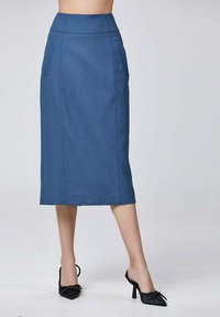 Jupe crayon bleue en tissu texturé, avec une taille haute, des poches latérales et une coupe droite, assortie à des talons noirs.