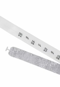 Weißes Maßband mit schwarzen Druckmaßen neben einem silbernen, texturierten Band mit floralem Spitzenmuster.