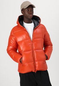 Orange puffer jacket with a glossy finish, featuring a zip front, hood, and two side pockets. Interior lined in black fabric.