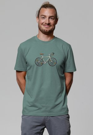 Mintgroene katoenen t-shirt met een fietsafbeelding in crème met zwarte accenten, bruine handvat en gedetailleerde wielen. Korte mouwen, ronde hals.