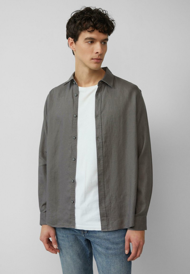 Grijze, lange mouwen overhemd met knopen in een lichte stof, met een relaxte fit en donkere knopen, gedragen over een wit T-shirt en denim jeans.