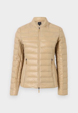 Doudoune beige clair au design ajusté, texture matelassée, col montant, fermeture éclair à l'avant et poches latérales. Arborant un branding minimal.
