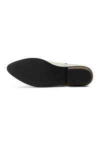 Suela de zapato plana con un acabado negro suave, que presenta una forma ligeramente curvada y un sutil detalle de costura a lo largo del borde.