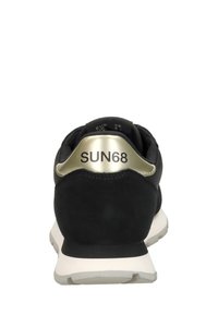 Zapatilla negra con parte superior de ante y suela blanca. Presenta un acento dorado en el talón con "SUN68" impreso. La vista trasera muestra líneas suaves.