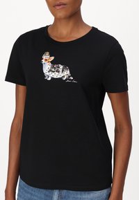 Zwarte t-shirt met een kleurrijke illustratie van een corgi met een bloemenpatroon en een kroon. Korte mouwen en een ronde halsontwerp.
