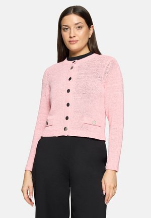 Cardigan rose en maille avec manches longues, encolure ronde et boutons noirs. Poches remarquables avec accents circulaires à l'avant.