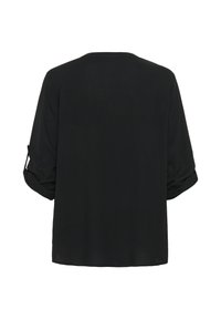 Chemise noire à manches longues, en tissu texturé, coupe décontractée. Présente des manches retroussées fixées par des pattes, un col rond et un ourlet droit.
