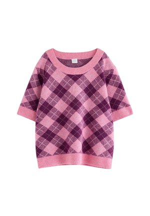 Junge Frau trägt einen rosa-lila Argyle-Kurzarmpullover und Rock, schwarze Stiefel und trägt eine schwarze Umhängetasche.