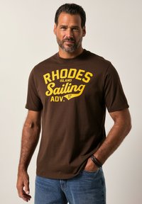 Hnědé bavlněné tričko s výrazným žlutým textem "RHODES ISLAND Sailing ADV." Krátké rukávy, kulatý výstřih, volný střih.