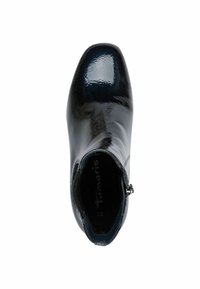 Botte de cheville en cuir verni noir avec un bout rond et une fermeture éclair, présentant une texture lisse et un subtil brillant ; doublure intérieure avec logo visible.