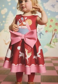 Czerwona sukienka z różową kokardą, z motywem górskim i wzorami zwierząt. Wykonana z gładkiej tkaniny, o długości do kolan i rozkloszowanym fasonie.