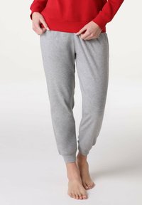 Pantaloni jogger grigi in cotone con polsini alle caviglie, vita elastica e vestibilità rilassata, abbinati a una maglia rossa a maniche lunghe.