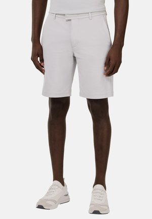 Pantalones cortos gris claro hechos de una tela suave, con un frente plano, corte clásico y pasadores para cinturón. Combinados con zapatillas blancas.
