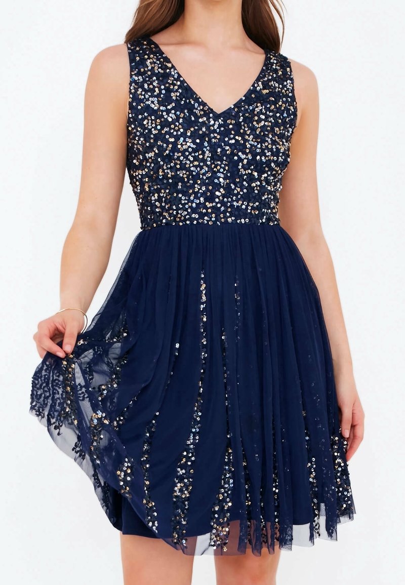 Robe bleu marine avec un décolleté en V, un corsage orné de sequins dorés et argentés, et une jupe en chiffon fluide avec des accents en dentelle.