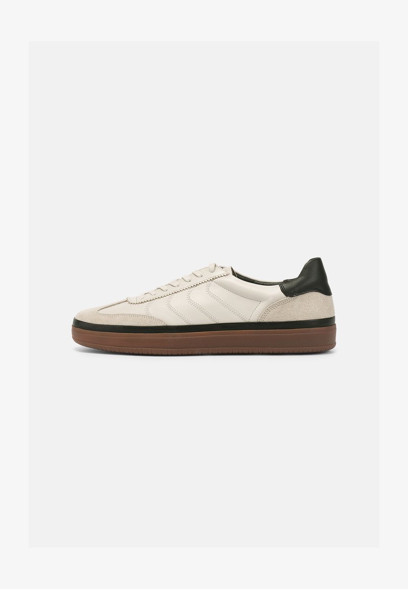 Lace-up sneaker in cream leather and beige suede, featuring a green heel accent, textured stripes, and a brown rubber sole.