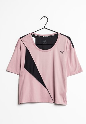 T-shirt d'entraînement rose Puma avec panneaux en mesh diagonaux noirs suspendu à un cintre noir sur fond blanc.