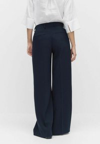 Pantalons larges bleu marine avec une texture de tissu lisse, présentant un design taille haute, des passants de ceinture et deux poches arrière.
