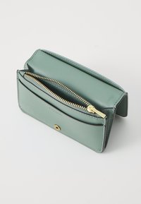 Green leather wallet with a zip closure, gold-tone zipper, and a decorative snap button. Features smooth texture and compact design.