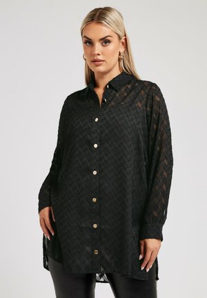Sort, gennemsigtig skjorte med knapper og et tekstureret zigzag-mønster, lange ærmer og knapper i guld-tone. Slidsider for ekstra komfort.