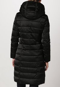 Schwarze Daunenjacke mit Kapuze, ausgestattet mit einem gesteppte Design, langen Ärmeln und einem geraden Schnitt, der einen eleganten Look und hohen Komfort bietet.