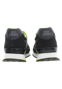 Scarpe nere con pannelli in suede e mesh, caratterizzate da un accento verde, tacco imbottito e suola bianca. Parte posteriore con la scritta "SINCE 1890" in argento.