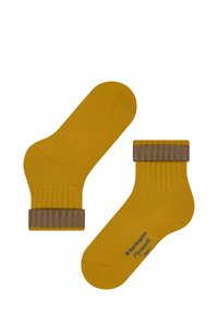 Chaussettes jaunes jusqu'aux chevilles avec un poignet côtelé marron. Le tissu semble lisse, présentant un logo près de la zone des orteils pour le branding.