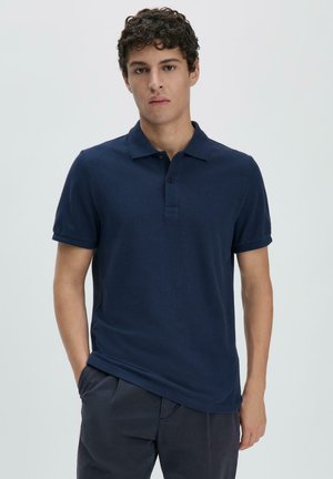 Polo di colore blu navy realizzato in tessuto testurizzato, con colletto classico, maniche corte e chiusura con due bottoni.