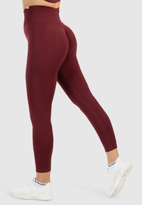 Leggings bordeaux taille haute au design ajusté et à la texture lisse, avec une finition sans couture et une silhouette allongeant les jambes.