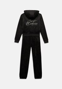 Juodas veliūro treniruočių kostiumas su užtrauktuku ir gobtuvu, ant kurio yra sidabriniu siūlu išsiuvinėta „Juicy Couture“ logotipas, taip pat paderinti siaurėjantys kelnės.