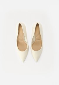 Ivory flats berbentuk runcing dengan eksterior kulit halus, desain minimalis, dan lapisan dalam berwarna beige muda. Tidak ada perangkat keras atau pola yang terlihat.